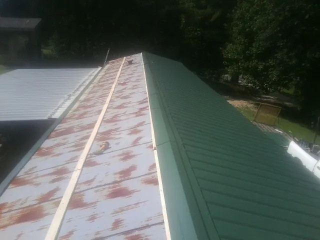 Old rusted panels beside newly installed green metal roofing — Wind Damage Roof Repair by Roofing Brothers in Cope