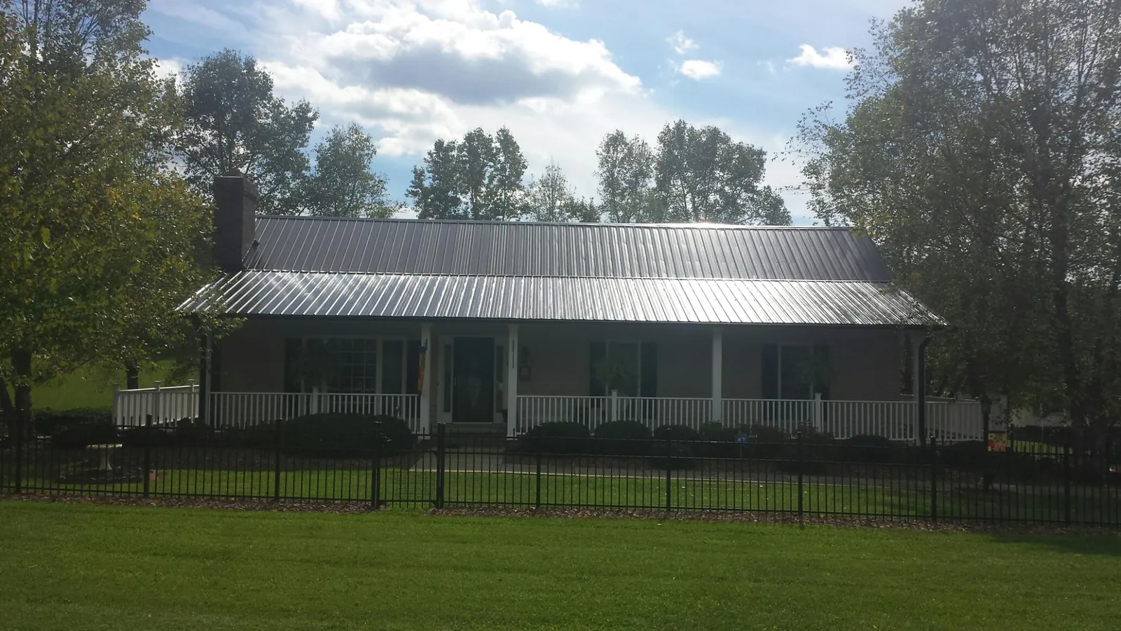 Gray metal roof on a brick ranch with a full width front porch — Gutter Guard Installation work by our crew in Cope