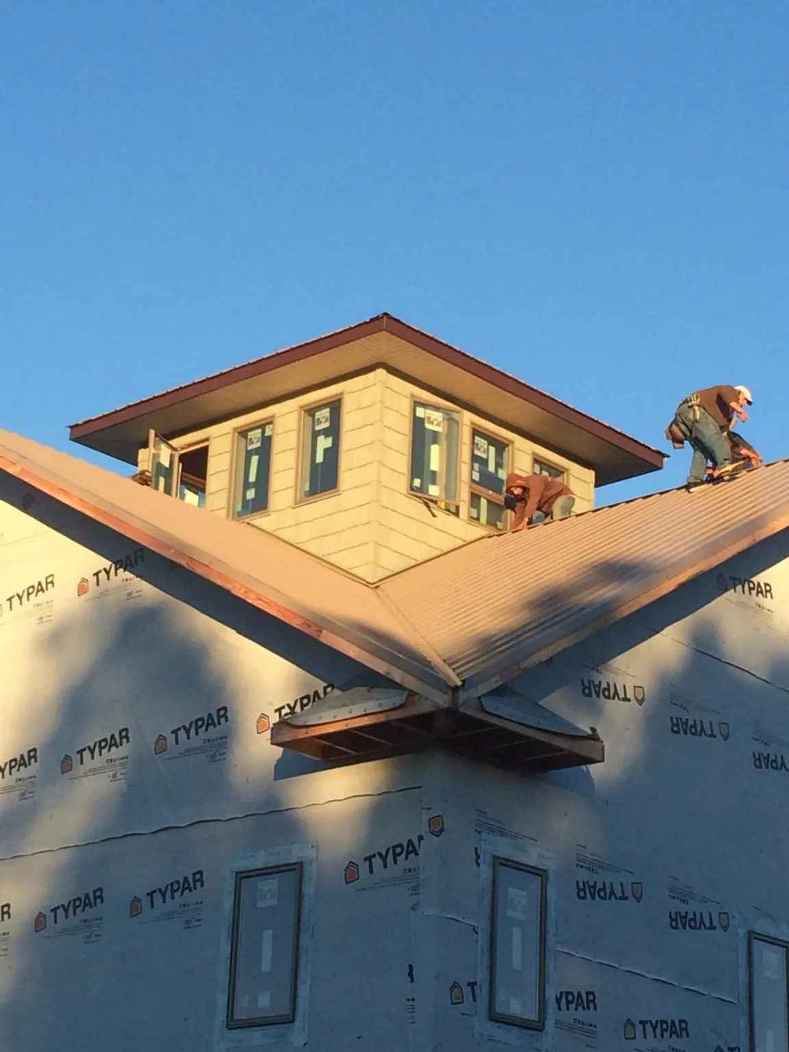 Roofers working around a rooftop cupola on a new metal roof at sunset — Roof Waterproofing in Cope by Roofing Brothers